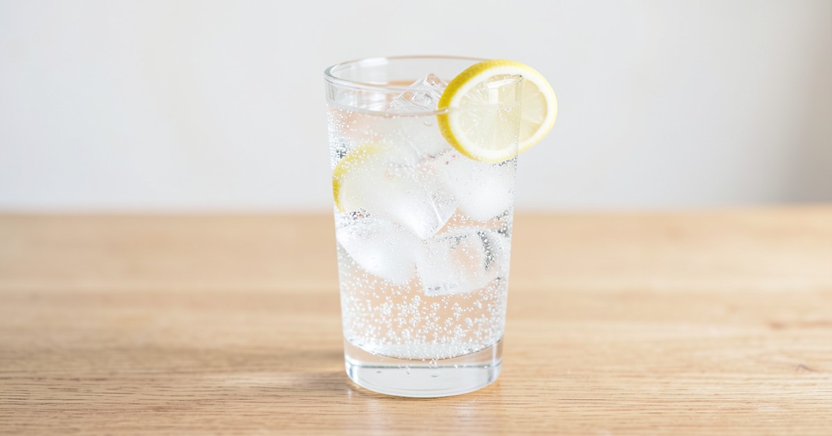 木製テーブルに置かれた、氷とレモンが入った炭酸水のグラス