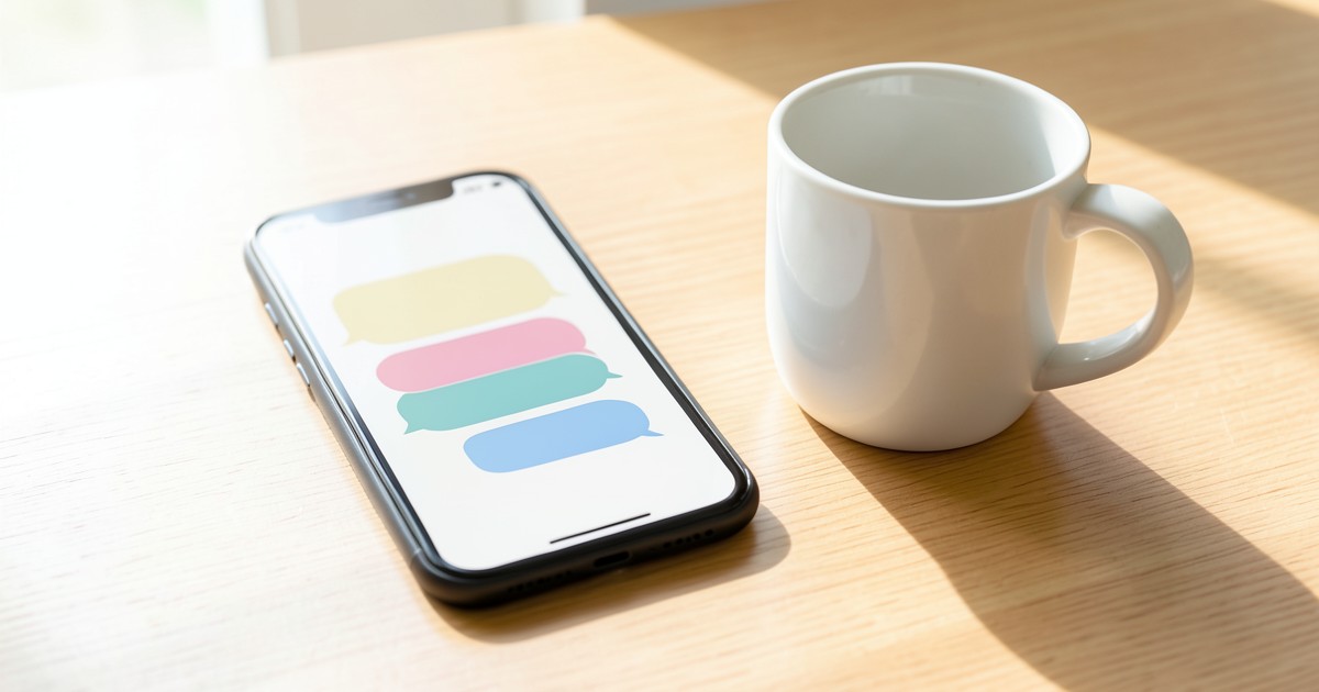 木目調のデスクに置かれたスマートフォンとコーヒーカップの風景