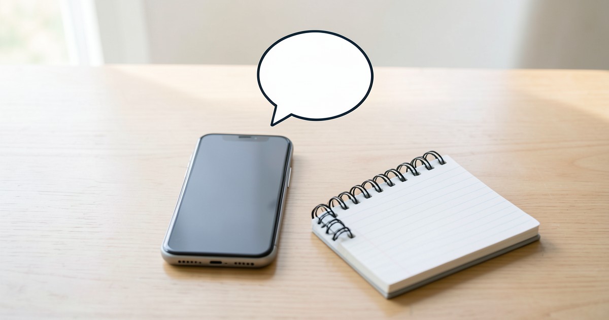 スマートフォンとメモ帳が置かれたデスク。フィードバックや意見を伝えることを象徴するイメージ。